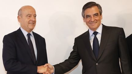 Alain Juppé (G) et François Fillon se serrent la main au siège de la Haute Autorité de la primaire à droite, à Paris, le 27 novembre 2016. (FRANÇOIS GUILLOT / AFP)