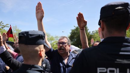 Des sympathisants du fascisme font le salut fasciste devant la police à l'extérieur du cimetière de San Isidro à Madrid, où le fondateur de la Phalange, Jose Antonio Primo de Rivera, sera enterré après son exhumation de la basilique Valle de los Caidos, officiellement nommée Valle de Cuelgamuros, le 24 avril 2023. (THOMAS COEX / AFP)