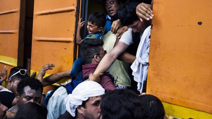 Les migrants tentent par tous les moyens de monter dans un train en direction des pays du nord de l'Europe le 5 ao&ucirc;t 2015 &agrave;&nbsp;Gevgelija, ville-&eacute;tape de la&nbsp;fronti&egrave;re gr&eacute;co-mac&eacute;donienne.&nbsp;Au m&ecirc;me moment, la Hongrie construit un mur anti-migrants &agrave; sa fronti&egrave;re. (DIMITAR DILKOFF / AFP)