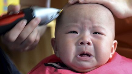 Un b&eacute;b&eacute; pleure alors qu'il se fait raser la t&ecirc;te &agrave; l'occasion du traditionnel festival&nbsp;Longtaitou &agrave; Zhengzhou (Chine), le 21 mars 2015. ( CHINA DAILY / REUTERS)