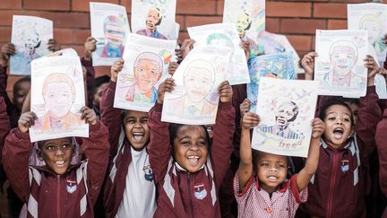 Des élèves brandissent&nbsp;des&nbsp;dessins de l'ancien président Nelson Mandela à l'occasion de son anniversaire à Durban, le 18 juillet 2019. (RAJESH JANTILAL / AFP)