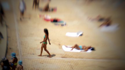 Plage artificielle d'une piscine en plein air, &agrave; Lyon (Rh&ocirc;ne). En pleine canicule, les enfants souffrent de la chaleur m&ecirc;me sous un parasol. (JEAN-PHILIPPE KSIAZEK / AFP)