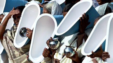 A la veille de la Journée mondiale des toilettes, des Indiennes brandissent des latrines, le 18 novembre 2014, à New Delhi. (AFP PHOTO/Roberto SCHMIDT)