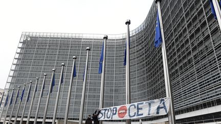 Deux hommes installent une pancarte "stop Ceta" devant les quartiers de la commission européenne à Bruxelles (Belgique), le 27 octobre 2016. (JOHN THYS / AFP)