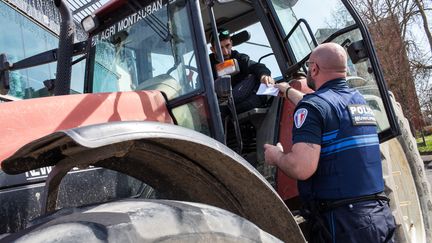 Un policier contrôle le conducteur d'un tracteur pour vérifier qu'il a son attestation de déplacement, le 18 mars 2020 à Montauban (Tarn-et-Garonne). (PATRICIA HUCHOT-BOISSIER / AFP)