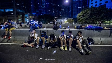 Des manifestants pro-d&eacute;mocratie consultent leur t&eacute;l&eacute;phone, &agrave; Hong Kong, le 29 septembre 2014.&nbsp; (XAUME OLLEROS / AFP)