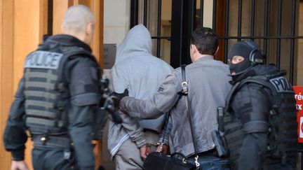 Le suspect de l'agression d'un militaire &agrave; La D&eacute;fense, escort&eacute; par les policiers, le 29 mai 2013, apr&egrave;s son arrestation.&nbsp; (ERIC FEFERBERG / AFP)