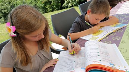 Des enfants s'appliquent à remplir&nbsp;leurs cahiers de vacances, le 15 juillet 2013. (MAXPPP)