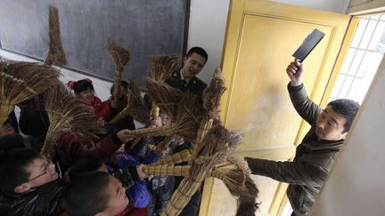 Des enfants apprennent &agrave; se d&eacute;fendre avec un balai dans une &eacute;cole primaire de Rugao (Chine), le 7 janvier 2013. (CHINA DAILY / REUTERS)