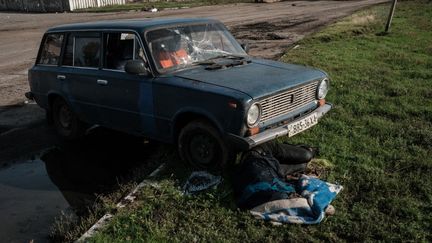 Un corps gît sous une voiture à Koupiansk, dans l'est de l'Ukraine, le 29 septembre 2022.&nbsp; (YASUYOSHI CHIBA / AFP)