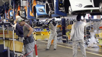 Des ouvriers de PSA assemblent des Peugeot 207 et 208 dans l'usine de Poissy (Yvelines), le 27 janvier 2012. (THOMAS SAMSON / AFP)