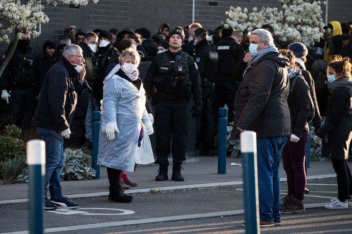 Des migrants attendent pour monter dans un bus qui doit les conduire dans un lieu de relogement après l'évacuation de leur campement à Aubervilliers (Seine-Saint-Denis) le 24 mars 2020. (JOEL SAGET / AFP)