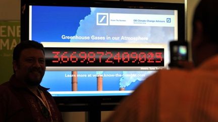 Un visiteur devant un compteur comptabilisant les gaz à effet de serre dans l'atmosphère. (AFP. C.Bouroncle)