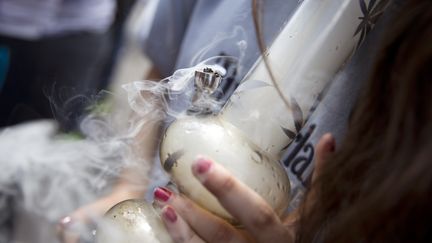 Une femme fume du cannabis lors d'une manifestation pour la légalisation de la marijuana à Paris, le 9 mai 2015. (KENZO TRIBOUILLARD / AFP)