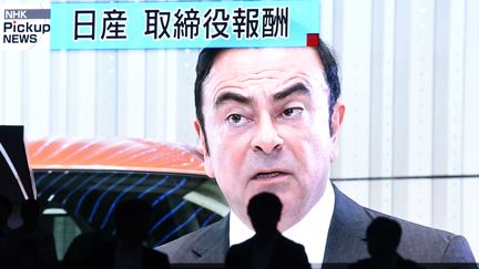 Des gens passent devant un écran géant qui diffuse des images de Carlos Ghosn, patron de Renault-Nissan-Mitsubishi, à Tokto (Japon), le 20 novembre 2018.
 (TOSHIFUMI KITAMURA / AFP)