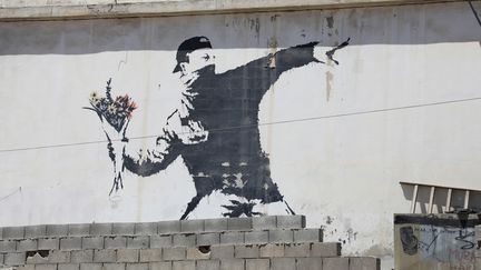 Une photo du dessin&nbsp;" Man Throwing Flowers"&nbsp;réalisé sur un mur de&nbsp;Bethléem par Banksy, en 2003. (HIROYUKI TAIRA / YOMIURI)