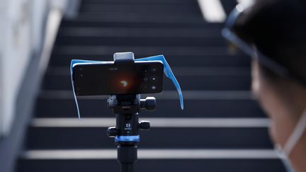 A Pékin (Chine), cet homme a utilisé une autre technique pour observer le phénomène astronomique : le filmer avec son smartphone. (TINGSHU WANG / REUTERS)