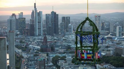 le gros œuvre est terminé et une cérémonie est organisé pour l’occasion. Comme le veut la tradition allemande, une couronne (végétale, sertie des 27 drapeaux membres et du drapeau de l'Union européenne) est posée au sommet de la tour.  
 

 
 
 
  (European Central Bank/Klaus Helbig)