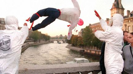 Le 17 octobre 1997, deux personnes jettent un mannequin dans la Seine du pont Saint-Michel à Paris, lors d'un rassemblement en souvenir des Algériens tués par la police lors d'une manifestation le 17 octobre 1961. (JOEL ROBINE / AFP)