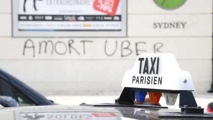 Un graffiti "A mort Uber" s'affiche derri&egrave;re les conducteurs de taxi porte Maillot &agrave; Paris, le 25 juin 2015. (CITIZENSIDE / ANTHONY DEPERRAZ / CITIZENSIDE.COM)