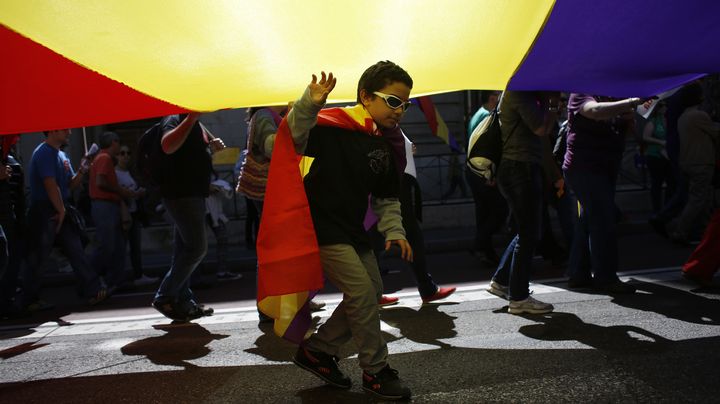 Un enfant joue sous un drapeau g&eacute;ant, lors du 82e anniversaire de la Seconde R&eacute;publique espagnole, dimanche 14 avril. (SUSANA VERA / REUTERS)