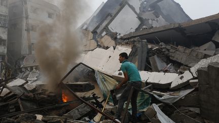 Un Palestinien fouille les d&eacute;combres d'un immeuble d&eacute;truit par une frappe isra&eacute;lienne, mardi 26 ao&ucirc;t 2014, &agrave; Gaza. (MOHAMMED ABED / AFP)