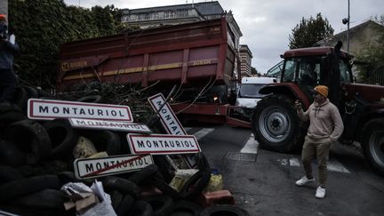 Un représentant de la Coordination rurale, devant des panneaux de villes, des pneus et divers déchets déversés devant la préfecture du Lot-et-Garonne, le 19 novembre 2024 à Agen. (THIBAUD MORITZ / AFP)