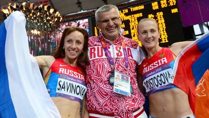 Sur le podium des athlètes russes accusés de dopage, Maria Savinova (à gauche), médaille d'or aux JO de Londres en 2012, et Ekaterina Poistogova, médaille de bronze, ici avec leur entraîneur Vladimir Kazarine, le 11 août 2012. (AFP photo / Franck Fife)