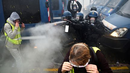 Des policiers aspergent de gaz lacrymogène des manifestants, le 1er décembre 2018, à Paris. (LUCAS BARIOULET / AFP)