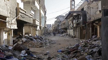 Des habitants marchent dans les décombres à Tadamon, un quartier de Damas (Syrie), le 3 novembre 2018. (LOUAI BESHARA / AFP)