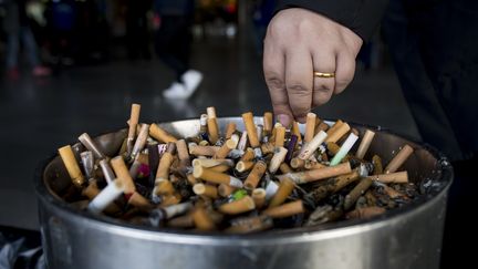 Un fumeur écrase sa cigarette dans une station de métro de Shanghai (Chine), le 28 février 2017. (JOHANNES EISELE / AFP)