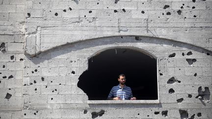 Un Palestinien contemple, depuis son immeuble marqu&eacute; par des &eacute;clats d'obus, les restes d'un batiment touch&eacute; par une frappe a&eacute;rienne, le 24 juillet &agrave; Gaza. (MAJDI FATHI / NURPHOTO / AFP)