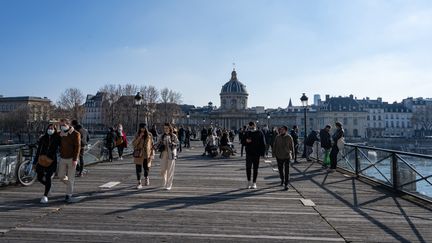 Des Parisiens profitent du soleil sur le Pont des Arts, lors du premier week-end du reconfinement, le 20 mars 2021. (SANDRINE MARTY / HANS LUCAS / AFP)