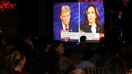 Les gens regardent le débat présidentiel américain entre Kamala Harris et Donald Trump, à New York le 10 septembre 2024. (LEONARDO MUNOZ / AFP)