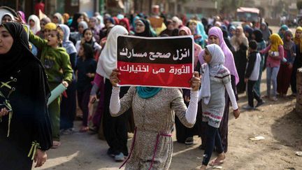 Des manifestants, le 11 novembre 2016, dans un quartier de Gizeh, près du Caire. Ils protestent contre les pénuries et les hausses de prix. «Manifeste pour le changement. La révolution est ton choix», peut-on lire sur la pancarte de la manifestante. (HESHAM FATHY / ANADOLU AGENCY)