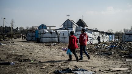 Deux jeunes migrants marchent dans la "jungle" de Calais (Pas-de-Calais), le 13 mars 2016. (JULIEN PITINOME / NURPHOTO / AFP)