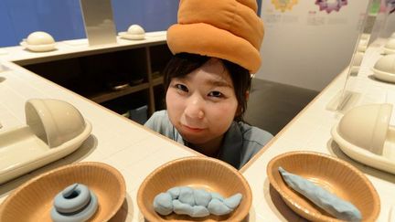 Une employée du musée national de l'innovation arbore un chapeau en forme d'étron, le 9 juillet 2014 au Japon, lors d'une exposition consacrée aux toilettes visant à éduquer les visiteurs sur les enjeux liés aux déchets et à la santé.  (AFP PHOTO/Toru YAMANAKA)