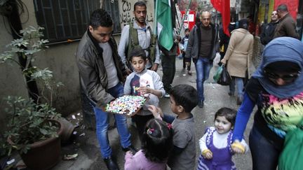 Distribution de friandises dans le camp libanais de Shatila, apr&egrave;s l'annonce de la mort d'Ariel Sharon.&nbsp;Human Rights Watch a jug&eacute; "regrettable que Sharon aille vers sa tombe sans r&eacute;pondre devant la justice de son r&ocirc;le &agrave; Sabra et Chatila". (ANWAR AMRO / AFP)