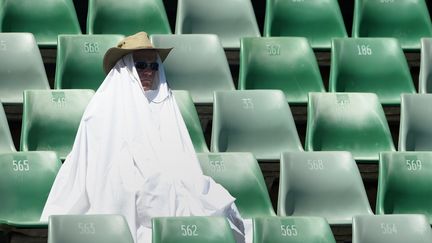 Dans les tribunes, les spectateurs se font rares. Et eux bravent la chaleur sont &eacute;quip&eacute;s. (WILLIAM WEST / AFP)