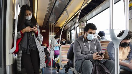 Des personnes regardant leur portable dans le métro à Paris, le 12 octobre 2020. (JEANNE FOURNEAU / HANS LUCAS / AFP)