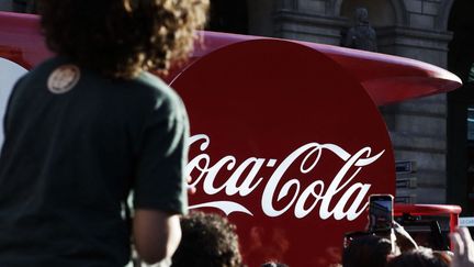 Un véhicule publicitaire Coca-Cola devant la flamme olympique, à Paris, le 14 juillet 2024. (NICOLAS RONGIER / AFP)