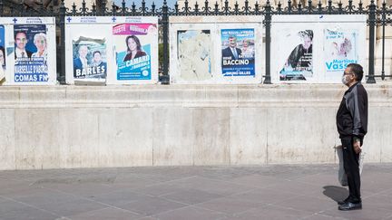 Un homme se tient devant les affiches des élections municipales organisées le 15 mars, le 16 avril 2020, à Marseille. (FABIEN DUPOUX/ SIPA)