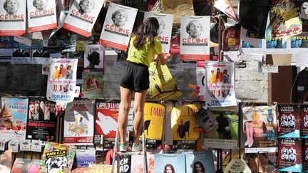 Le Off d'Avignon : une jeune femme installe ses affiches sur un mur de la ville, le 4 juillet 2018. (PATRICK ROUX / MAXPPP)