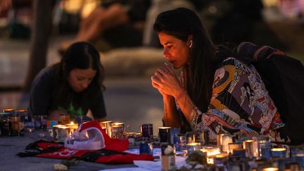 Une femme allume une bougie en hommage aux victimes israéliennes au bord de la fontaine de la place Dizengoff, à Tel-Aviv, le 18 octobre 2023. (AHMAD GHARABLI / AFP)