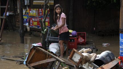 Une petite fille rassemble des affaires au milieu des d&eacute;combres boueux, &agrave; Cagayan De Oro city. (REUTERS)