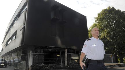 Un policier se tient devant le centre des imp&ocirc;ts &agrave;&nbsp;Morlaix, le 20 septembre 2014, au lendemain de l'incendie. (FRED TANNEAU / AFP)