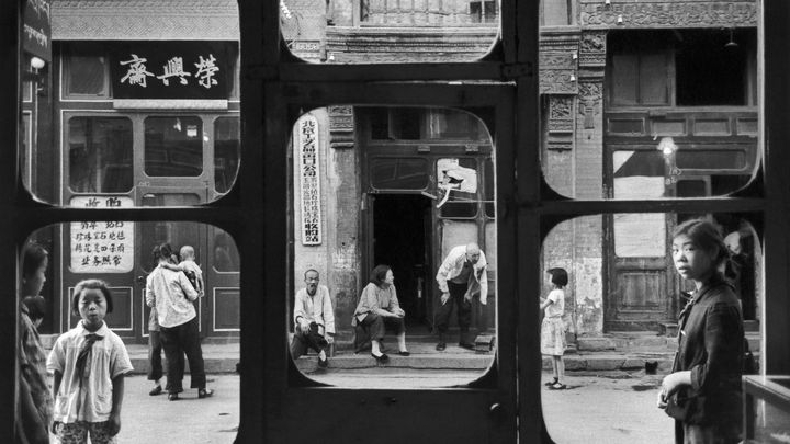 "Fenêtres d'antiquaire". Pékin, Chine 1965. La rue Liulichang à Pékin est célèbre pour ses antiquaires. Ici, les personnages semblent avoir été soigneusement disposés pour composer chacun une petite scène. (© Marc Riboud / Fonds Marc Riboud au MNAAG)