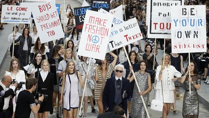 Avec pancartes et hauts-parleurs, Karl Lagerfeld a organisé une manif "féministe mais féminine" aux airs de mai 68 pour présenter une collection pleine de gaieté, en réaction à une époque jugée rétrograde. Le couturier avait planté le décor dans une rue typiquement parisienne, reconstituée sous la verrière du Grand Palais. Des photos géantes d'immeubles haussmanniens encadraient le podium. Le défilé commence dans une explosion de couleurs façon aquarelle psychédélique puis la palette redevient plus sobre, avec des ensembles blancs, noirs et marine. Au final, les mannequins emmenées par le couturier sont armées de pancartes bleu, blanc, rouge. "Divorce pour tous", réclame une pancarte, en réponse aux manifestants contre le mariage gay. "Be different", "Make Fashion Not War", proposent d'autres panneaux, clins d'oeil aux mouvements de contestation des années 60. En coulisses, le couturier a rendu hommage au "vent de liberté" qui soufflait en mai 1968 en France. "Aujourd'hui, tout est interdit, le politiquement correct a tout détruit (...) Les gens sont devenus bien plus bourgeois depuis", juge-t-il. "J'ai trouvé que c'était le moment d'insister (sur ce message) à nouveau, spécialement en France. "Ma mère était une féministe", raconte encore Karl Lagerfeld à l'AFP. Cette collection, il l'a voulue pleine de "gaieté et d'espoir" et plus "mode de vie que mode ". 
 (PATRICK KOVARIK)