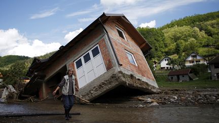 Une femme marche pr&egrave;s d'une maison d&eacute;plac&eacute;e par les inondations dans le village de Krupanj (Serbie), le 19 mai 2014.&nbsp; ( MARKO DJURICA / REUTERS)