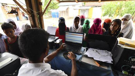 Des habitants d'Assam, en Inde, cherchent leur nom dans le registre national des citoyens.&nbsp; (BIJU BORO / AFP)